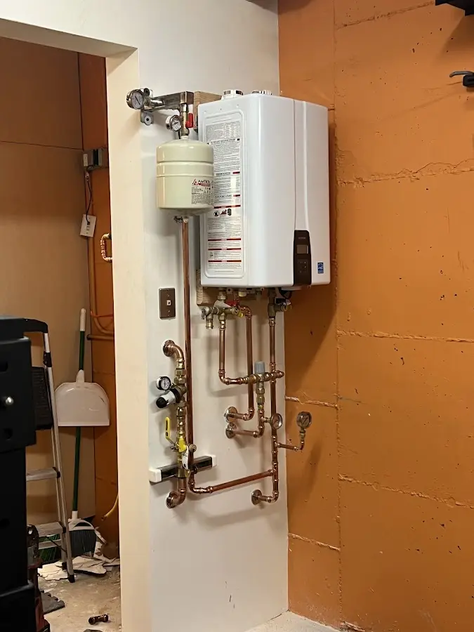 Plumbing technician inspecting water heater connections in Westborough